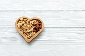 Healthy Foods. Mixed nuts in heart shape with nuts for diet on white wood. Different kinds of tasty and healthy nuts. Top view and copy space.  Healthy Concept