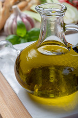 Virgin natural olive oil is glass bottle, served with traditional Mediterranean food