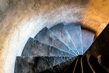 Old stone narrow spiral staircase inside the medieval tower