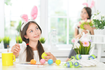 Obraz na płótnie Canvas Portrait of cute girl painting eggs for Easter holiday
