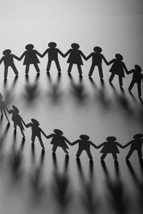 Paper people holding hands on white surface. Community, brotherhood concept. Society and support.