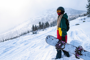 Female snowboarder freerider with snowboard in the mountains on a snowy slope.