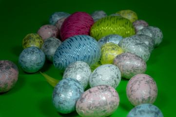 Handmade Easter eggs and yellow feathers on green