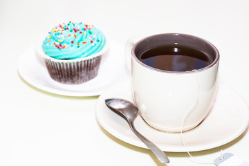 a Cup of tea and a beautiful cupcake on a white background
