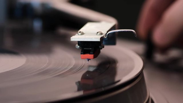 middle distance footage of vintage turntable starting play with focus on stylus