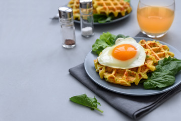 Spinach cheese waffles with fried egg on gray wooden background. Selective focus.
