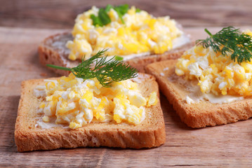 Crunchy toasted bread with scrambled eggs on rustic table