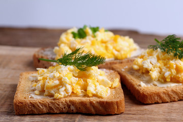 Toasted bread with scrambled eggs and fresh dill on it