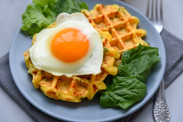 Spinach cheese waffles with fried egg on gray wooden background. Selective focus.