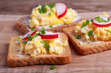 Toasted bread with scrambled eggs with fresh chives and radish for breakfast