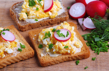 Fototapeta na wymiar Toasted bread with scrambled eggs with fresh chives and radish for breakfast
