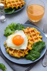 Spinach cheese waffles with fried egg on gray wooden background. Selective focus. Top view.