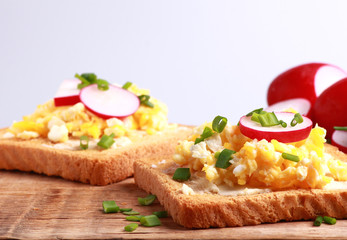 Tasty bread with scrambled eggs with chives and radish for breakfast