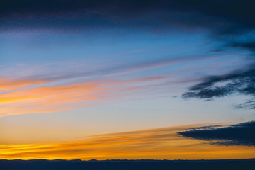 Obraz premium Amazing dramatic blue cloudy sky with orange sunshine in clouds. Atmospheric background in overcast weather. Storm warning. Beautiful dark cloudscape. Sunset. Sunrise. Dawn. Copy space.