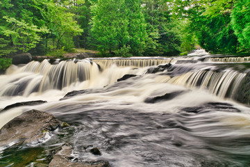 Fototapeta na wymiar A waterfall flows quickly in Michigan after a heavy rain along a hiking trail in the mountains