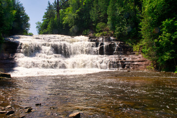 A waterfall flows quickly in Michigan after a heavy rain along a hiking trail in the mountains