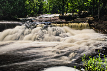A waterfall flows quickly in Michigan after a heavy rain along a hiking trail in the mountains