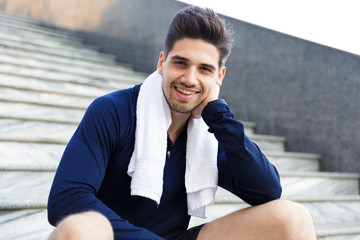 Fototapeta premium Smiling young sportsman sitting on a staircase