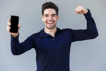 Cheerful young man showing blank screen mobile phone