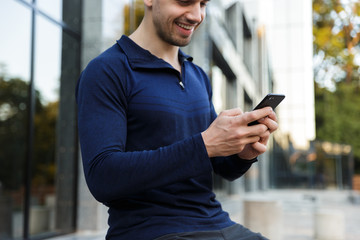 Croppped image of a sportsman using mobile phone