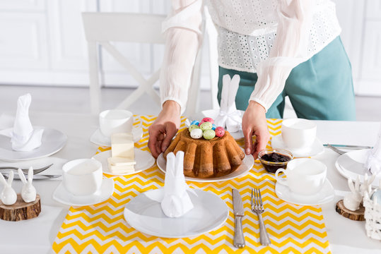Cropped view of woman in white blouse serving table for easter