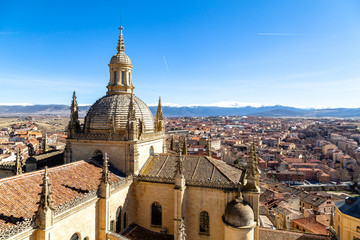 Obraz premium Segovia, Spain – View of the dome of the Cathedral and of Segovia old town from the top of the bell tower during Winter time. The snow capped peaks of Sierra de Guadarrama are visible behind
