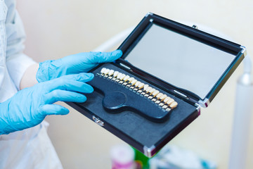 Doctor holds in his hands the color palette of teeth for whitening. oral treatment.