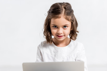 Concentrated preschooler kid using laptop while sitting on floor on white