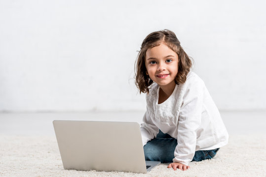 Concentrated Brunette Kid Looking Down While Using Laptop On White