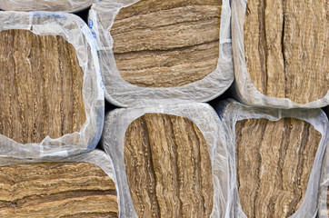 Pile of   round basalt mineral wool packages  in plastic foil .