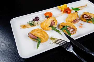 Mousse of cheese with bacon in eclair, covered with green and tomato cherry
