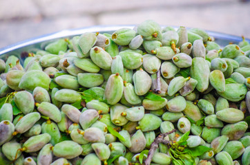 Metal plate with harvested raw green almonds on stone floor background