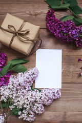 Bouquet of lilac flowers on wooden planks with gift.