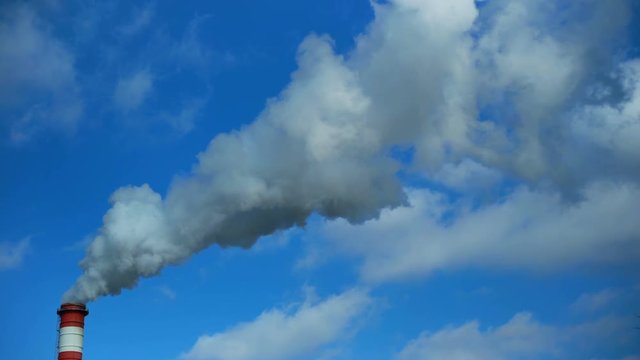 Power plant chimney smoke against cloudy blue sky. Air pollution. High Quality 4K video