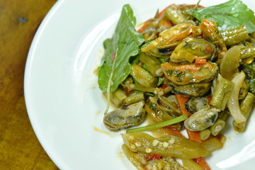 spicy stir fried mussel with basil leaf on plate