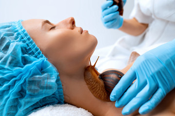 Naklejka premium Young woman undergoing treatment with giant Achatina snails in beauty salon.