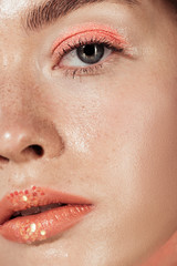 close up of woman with coral glitter makeup looking at camera