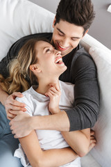 Image of lovely couple man and woman hugging together while sitting on sofa at home
