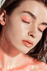 beautiful stylish girl covered in coral glitter posing with eyes closed