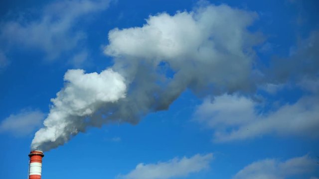 Power plant chimney smoke against cloudy blue sky. Air pollution. High Quality 4K video