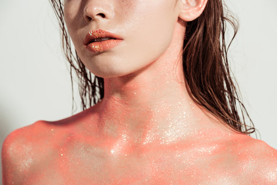 cropped view of nude woman with coral glitter and wet hair isolated on grey