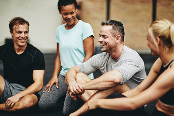 Diverse friends laughing on a gym floor after working out