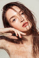 beautiful young woman with coral lips touching face and looking at camera near aquarium isolated on...