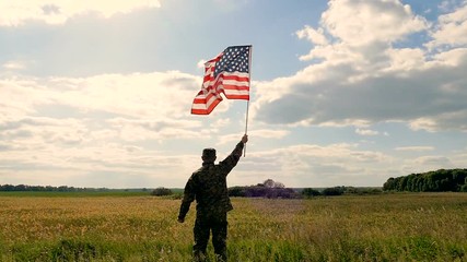 Soldier lifted up American flag against    blue sky. Outdoor slow motion scene