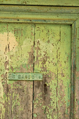 Ancient front door with light green painted plaque.