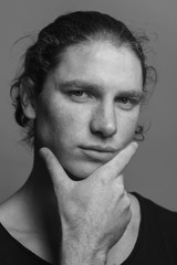 Portrait of a handsome long-haired man with drawn hair and freckles wearing a black T-shirt