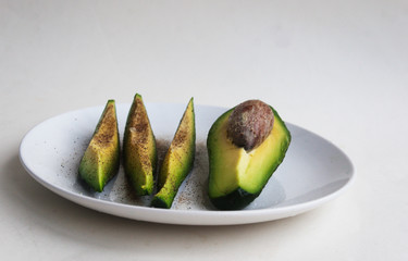Avocado slices with salt and pepper on a plate. Candid.