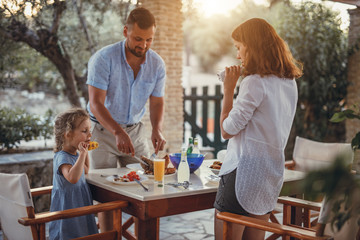 Father and dauther having mediterranean dinner on a terrace in a olive garden during summer vacation