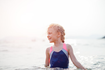 Little girl making a splash while being in the sea water soaking wet
