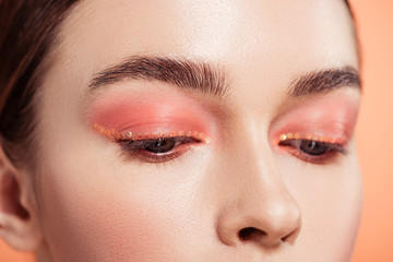 close up of beautiful woman with makeup posing isolated on coral